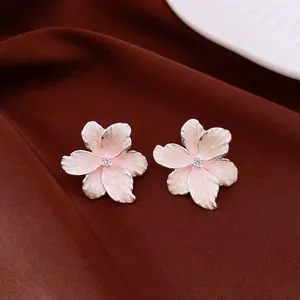 Elegant flower-shaped stud earrings with zircon center on a dark brown textured background