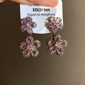 Close-up of elegant pink flower zircon dangle earrings attached to a white jewelry tag