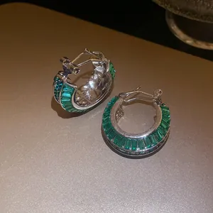 Vista dettagliata degli orecchini a cerchio in argento con zirconi verde smeraldo.