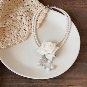 Collier à double rangée de perles avec rose en tissu blanc et pendentif à pompon.