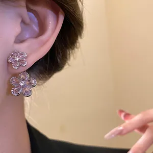 Detailed close-up of vintage style pink zircon flower drop earrings worn on an ear lobe