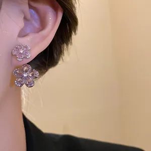 Detailed close-up of pink zircon flower earrings on model ear, showing sparkling texture
