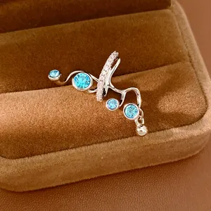 Close-up of elegant silver-tone ear cuff featuring blue zircons and clear crystals