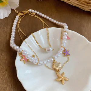 Detail view of layered pearl necklace with golden shell and colorful starfish charms