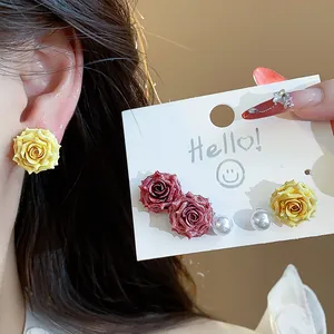 Close-up of sweet French resin rose and pearl stud earrings on model