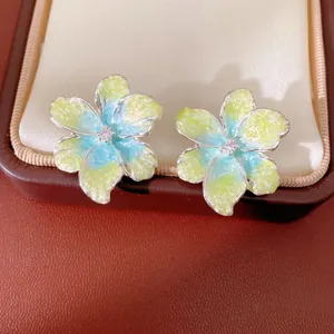 Macro view of delicate gradient yellow and blue flower stud earrings with center zircon