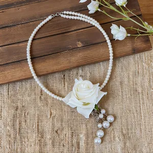 Vue détaillée de la rose en tissu blanc et des glands en perles sur un collier élégant