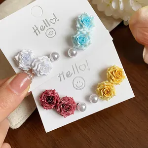 Detailed close-up showing a set of colorful resin rose and pearl stud earrings on cards.
