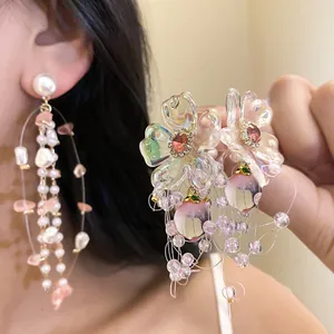 Detailed view of elegant floral earrings with peach drops and long pearl tassels.