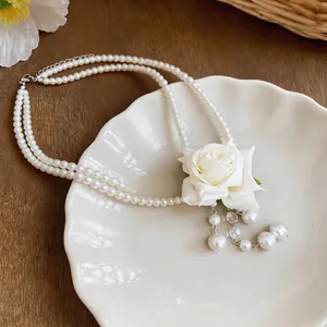 Détail élégant d'un collier de perles à double rangée avec rose en tissu blanc et glands.