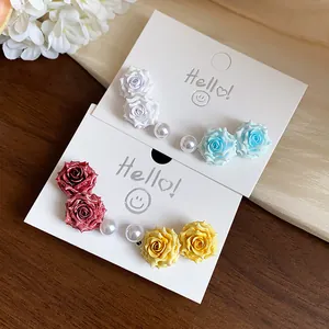 Detailed view of sweet resin flower and pearl stud earrings on white display cards.