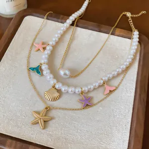Close-up of multi-layer pearl necklace featuring enamel starfish and gold shell charms