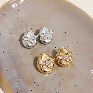 Detailed macro view of teardrop stud earrings with zircon butterfly design in gold and silver