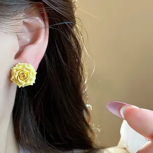 Close-up detail of a sweet French style yellow resin rose flower earring on ear