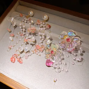 Macro detailed view of iridescent flower and pearl tassel earrings displayed in a velvet jewelry box