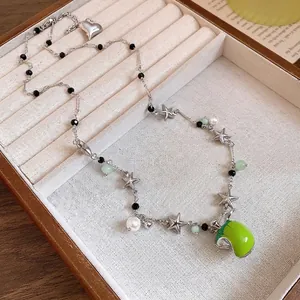Collier élégant perles étoiles avec pendentif pomme verte dans un plateau à bijoux.