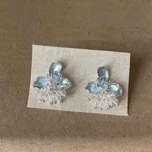 Eleganti orecchini a lobo a fiore in smalto blu con nappine di cristallo scintillanti su espositore