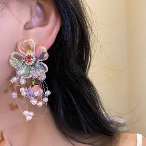 Close-up of zircon floral earrings with peach pendant and pearl tassels on a model