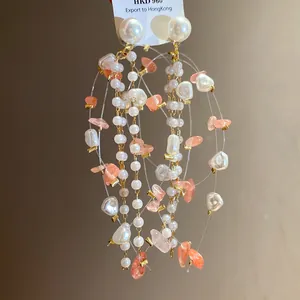 Macro view showing the delicate pearl and peach stone beads on these tassel earrings.