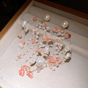 Detailed macro view of elegant pearl earrings featuring delicate pink stone tassels on gold chains