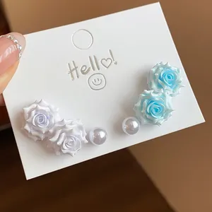 Detail view of sweet resin rose and pearl earring set on a white display card.