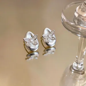 Detailed view of elegant silver-plated butterfly zircon stud earrings on a gold surface