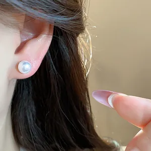 Detailed macro view of a single elegant white pearl stud earring worn on a person's earlobe.
