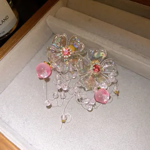 Detail view of iridescent floral tassel earrings featuring delicate pink peach charms