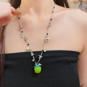 Gros plan du collier argenté avec des breloques étoiles, des perles et une pomme verte