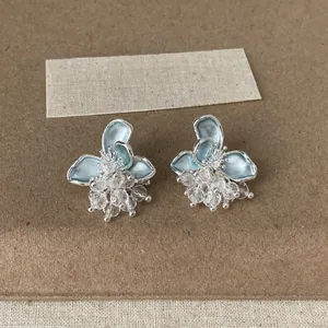 Dettaglio di eleganti orecchini a fiore in smalto azzurro con nappe di cristallo