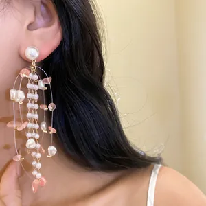 Detailed close-up of elegant long tassel earrings with pearls and pink stones