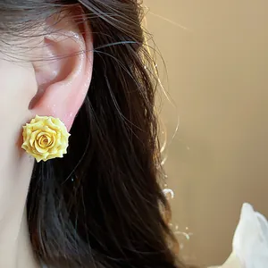 Close-up showing the intricate texture of a yellow resin rose stud earring on an ear.
