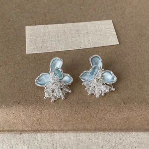 Primo piano di petali di fiori in smalto blu e nappe di perline di cristallo luccicanti.