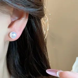 Macro view of an elegant white pearl stud earring worn on the ear showing detail
