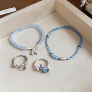 Set of light blue fish-themed jewelry including beaded bracelets and silver rings for summer