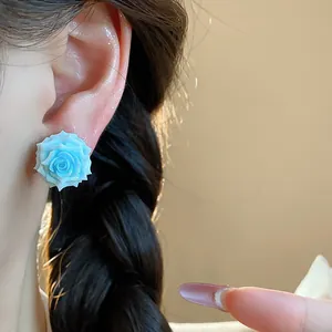 Detailed close-up of a sweet blue resin rose ear stud with delicate flower petals.