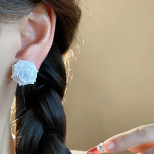 Close-up of elegant white resin rose stud earring worn on a female ear for style