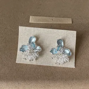 Dettaglio di orecchini a fiore in smalto blu con nappe di perline di cristallo