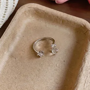 Silver open ring with square gemstone and clear beads on textured tray background