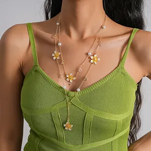 Close-up view of a model wearing a two-piece gold-tone necklace set with pearls and flowers.
