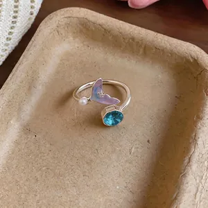 Macro detail of adjustable silver mermaid tail ring with blue crystal and small pearl