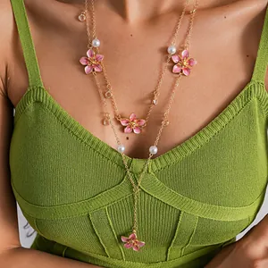 Close-up detail of a double-layer necklace featuring pink enamel flowers and pearls