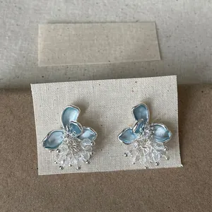 Primo piano dettagliato di eleganti orecchini a fiore in smalto blu e nappe di cristallo