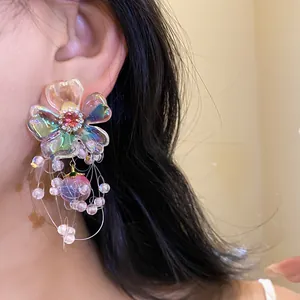 Close-up detail of a colorful iridescent floral earring with zircon center and bead tassels