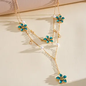 Detail of a double-layered gold necklace with blue enamel flowers and pearls