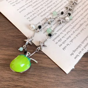 Gros plan d'un collier avec pendentif pomme, étoiles argentées et détails de perles