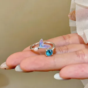 Close-up view of an elegant mermaid tail silver ring with blue gemstone and pearl