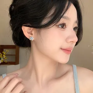 Detailed close-up showing a delicate light blue star-shaped stud earring on a model