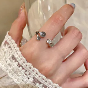 Detailed view of silver open ring with grey beads and square clear stone