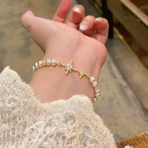 Detail shot of an elegant pearl bracelet featuring sparkling gold star charms and zircon